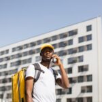 African delivery male speaks to a customer using a mobile phone to order fast food delivery.