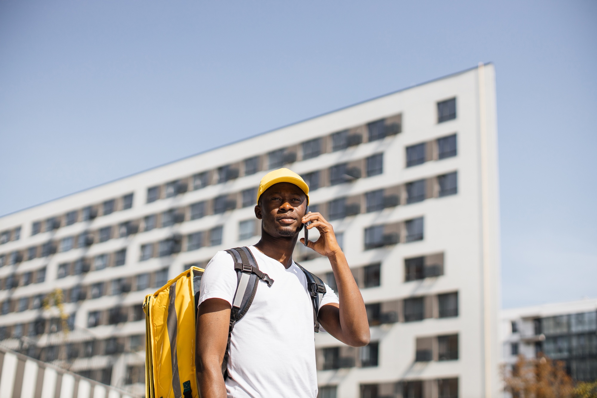 African delivery male speaks to a customer using a mobile phone to order fast food delivery.