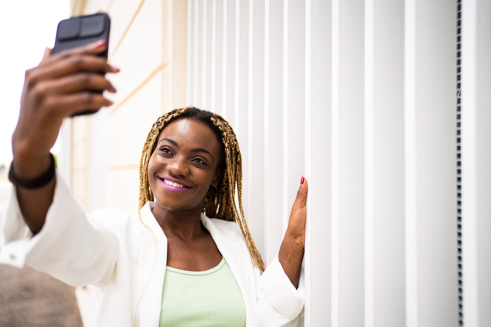 Smiling young adult african woman taking selfie with a mobile outdoors